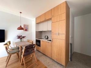 a kitchen with wooden cabinets and a table and chairs at Len Apartments One Gdańsk Sobieszewo Baltic Line blisko morza na Wyspie Sobieszewskiej dla rodzin przyjazny zwierzętom z tarasem in Gdańsk +32 photos