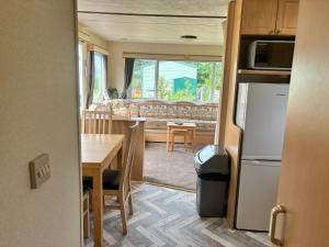 a kitchen and living room with a table and a refrigerator at Cadwgan Caravan No2 in Barmouth