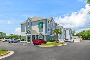 a hotel with cars parked in a parking lot at Quality Inn Shallotte near Ocean Isle Beach in Shallotte