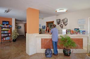 Ein Mann und eine Frau stehen an einer Theke in einer Apotheke in der Unterkunft Apartamentos Doramar in Benalmádena