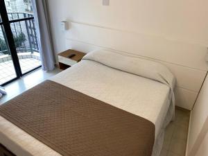 a bed in a room with a large window at Atlantico Flat Santos in Santos +10 photos