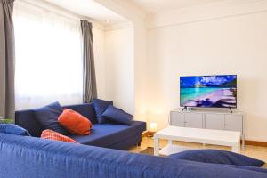 salon z niebieską kanapą i telewizorem w obiekcie Apartamento Natalia w mieście Puerto de Gandía