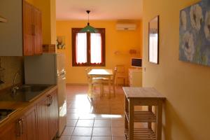 eine Küche mit einem Tisch und eine Küche mit gelben Wänden in der Unterkunft Appartamenti Le Cicale in Fertilia