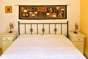 ein Schlafzimmer mit einem weißen Bett und zwei Nachttischen in der Unterkunft Appartamenti Le Cicale in Fertilia