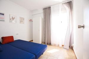 sypialnia z niebieskim łóżkiem i oknem w obiekcie Apartamento Natalia w mieście Puerto de Gandía