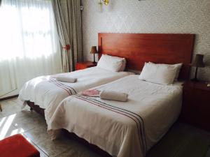 a bedroom with two beds with white sheets and a wooden headboard at Logos Guest House in Pietermaritzburg