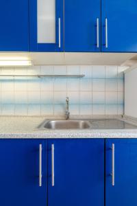 une cuisine avec des armoires bleues et un évier dans l'établissement Team Flat & Urban Family Comfort - HomeBase with a Castle view, à Petržalka