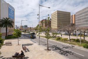 two people sitting on a bench in a city at Acogedor Apartamento Centro , Cerca de Plaza España y Barcelona in Hospitalet de Llobregat