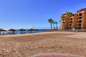 a sandy beach with umbrellas and the ocean at Princesa De Penasco in Punta Penasco New