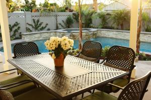 a table with flowers on a patio with a pool at Lavish 5 Bedroom, 4 Bath Pool Home 3/4 Mile To Disney in Anaheim
