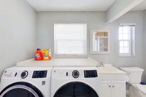 Aqua Vista Cape Coral Waterfront Haven في كيب كورال: غسالة ومجفف في غرفة غسيل بيضاء