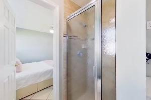 Aqua Vista Cape Coral Waterfront Haven في كيب كورال: دش زجاجي في حمام مع سرير