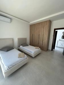a bedroom with two beds and a wooden cabinet at Villa Djerba 6 personnes in Arkou
