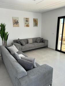 a living room with two gray couches in it at Villa Djerba 6 personnes in Arkou