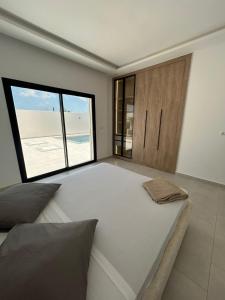 a large bed in a room with a large window at Villa Djerba 6 personnes in Arkou