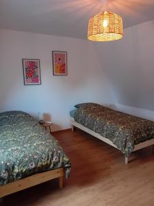 two beds in a room with a lamp at Le gîte de notre histoire in Épégard