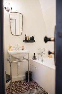 ein Badezimmer mit einem Waschbecken, einem Spiegel und einer Badewanne in der Unterkunft Marnie et Mister H in Rennes