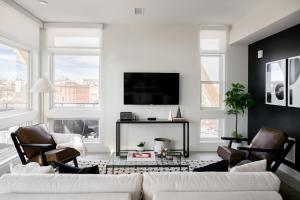 a living room with a white couch and a tv at Serenity in Style | Espadin LoHi in Denver