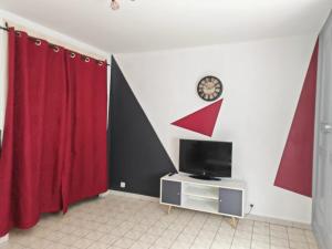 a living room with red curtains and a tv at RnB Locations Mâcon in Mâcon