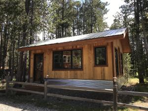 una cabina di legno nel bosco con una recinzione di West Yellowstone Bed and Breakfast a West Yellowstone
