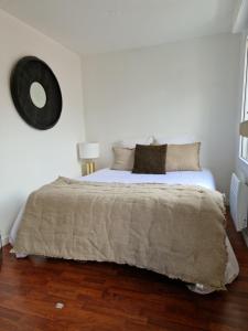1 dormitorio con 1 cama grande y reloj grande en la pared en Appartement hyper centre ville proche de la gare, en Toulouse
