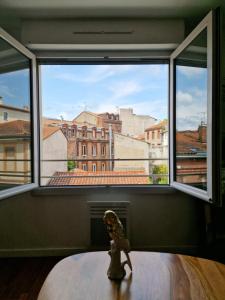 una pequeña estatua sentada en una mesa frente a una ventana en Appartement hyper centre ville proche de la gare, en Toulouse
