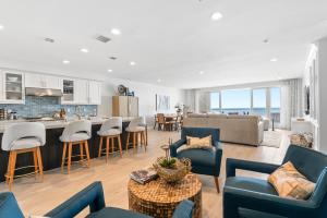 a living room with blue chairs and a kitchen at Oceanfront Penthouse Amazing Views in Oceanside