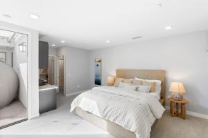 a white bedroom with a large bed and a bathroom at Oceanfront Penthouse Amazing Views in Oceanside