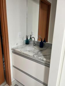 eine Badezimmerablage mit Waschbecken und Spiegel in der Unterkunft Apartamento no Condominio da Fé - Canção Nova in Cachoeira Paulista