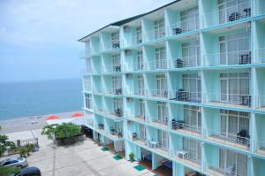 a blue hotel with the ocean in the background at Black Sea Hotel in Kvariati