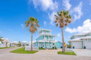 a blue house with palm trees in front of it at Blue Fin House- Pet Friendly & Boardwalk to the Beach! in Mustang Beach