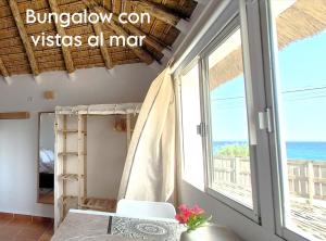 a room with a table and a window with a view of the ocean at Mandala Bungalows - Adults Only in Los Caños de Meca