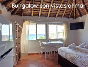 a bedroom with a bed and a table with a view of the ocean at Mandala Bungalows - Adults Only in Los Caños de Meca