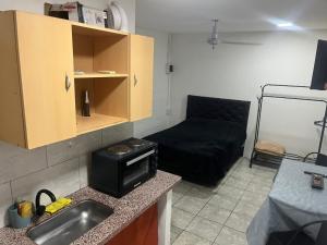 a kitchen with a microwave and a black couch at 3 Acogedor y confortable monoambiente in Santiago del Estero