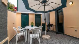 a patio with a table and chairs and an umbrella at Seaside House in Estreito in Estreito da Calheta