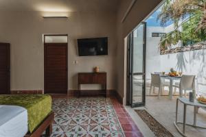 Un dormitorio con una cama, una mesa y un televisor. en Casa Tropical, en Mérida