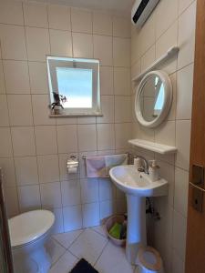 a bathroom with a sink and a toilet and a mirror at Apartment Orebic 10082b in Orebić