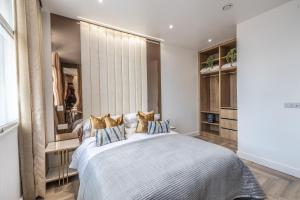 レスターにあるLuxury City Centre Apartment With Large Balcony Perfect For Couples & Businesses With Free Gym By The Pocklington - The Golden Mile Suiteのベッドルーム1室(大型ベッド1台、金の枕付)