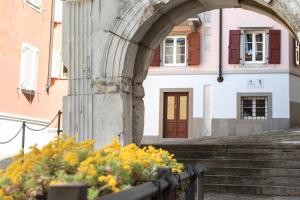 an archway in front of a building with stairs and flowers at Hotel All'Arco in Trieste