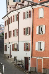 a white building with red shutters on a street at Hotel All'Arco in Trieste