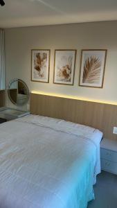 ein Schlafzimmer mit einem großen Bett mit vier Bildern an der Wand in der Unterkunft Beach Class Meireles Studio Mobiliado in Fortaleza