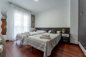 three beds in a room with white walls and wood floors at Casa San Martin in Cortiguera +36 photos