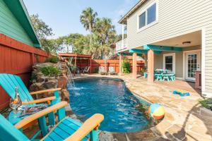 una piscina con sillas azules y una casa en Tortuga Inn, en Galveston