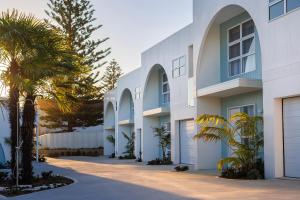 a building with palm trees in front of it at Olas Villa 5 - Plunge Pool & Walk to Beach in Anna Bay
