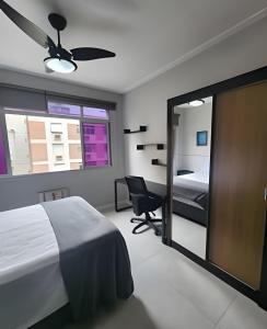 a bedroom with a bed and a chair and a mirror at Lindo Apto Beira Mar - Ponta da Praia - Santos in Santos