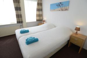 - 2 lits dans une chambre d'hôtel avec des serviettes bleues dans l'établissement Logies De Sering Texel, à De Koog