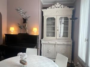 a white cabinet in a room with a table and a piano at Lovely house with garden Paris Flea Market in Saint-Ouen