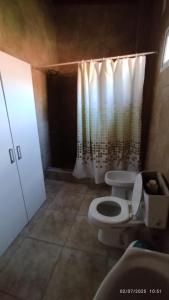 a bathroom with a toilet and a shower curtain at Finca la milagrosa in Santiago del Estero +8 photos