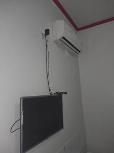 a flat screen tv on a wall with a fan at Pousada Itororó in Bom Jesus da Lapa