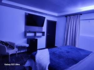 a bedroom with a bed and a flat screen tv at Cataleya suites blue in La Coyotera